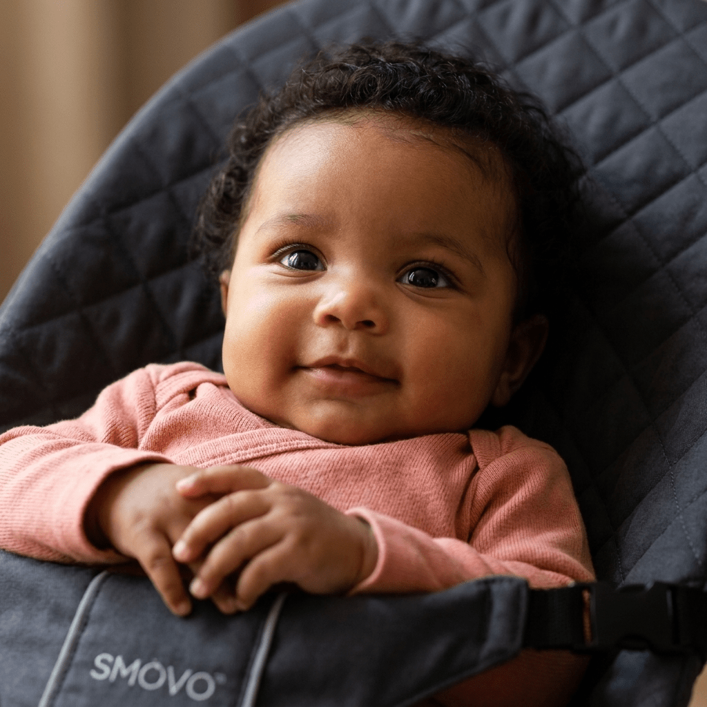 Nahaufnahme lächelndes Baby in SMOVO Babyschaukel – weiches Rautenmuster Stoff