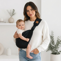 SMOVO Carry Baby Tragetuch – junge Mutter mit Baby 
im schwarzen Sling Träger, helles minimalistisches Zimmer